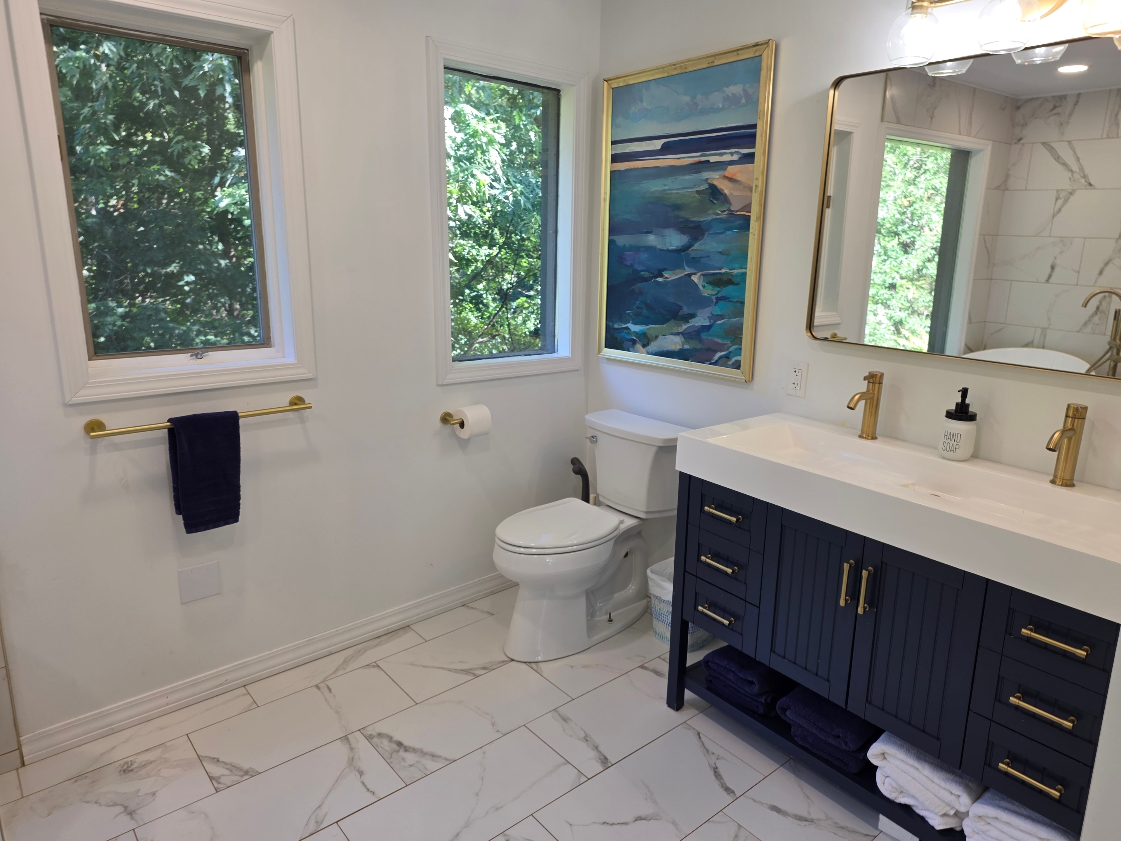 Navy vanity with gold fixtures and coastal artwork